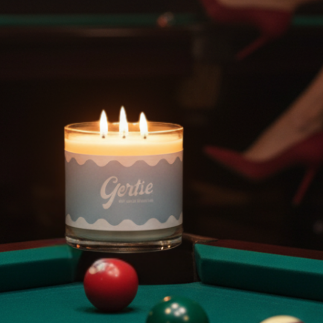 Candle labeled 'Gertie' on a pool table with pool balls.