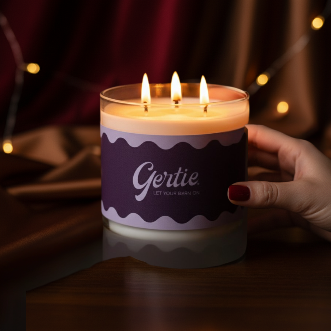 Candle with 'Gertie' branding held by a hand against a warm, blurred background