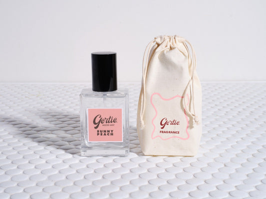 A bottle of 'Sunny Peach' room mist next to a drawstring bag, both with the brand name and the word 'Sunny' visible.