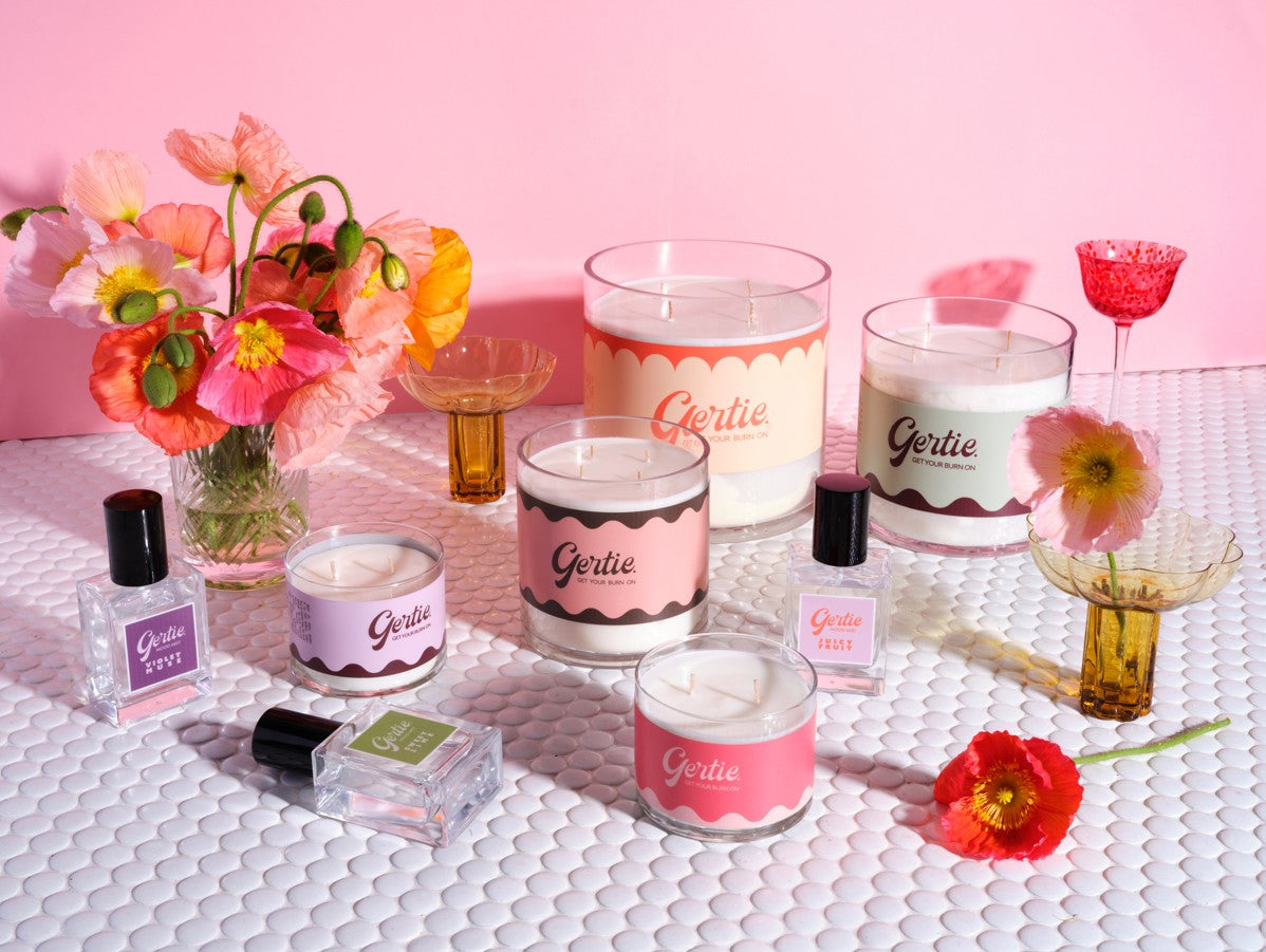 A colourful flatlay of Gertie candles and mood mists styled with poppies, vintage glassware, and scalloped labels - bold scents meet bold style.